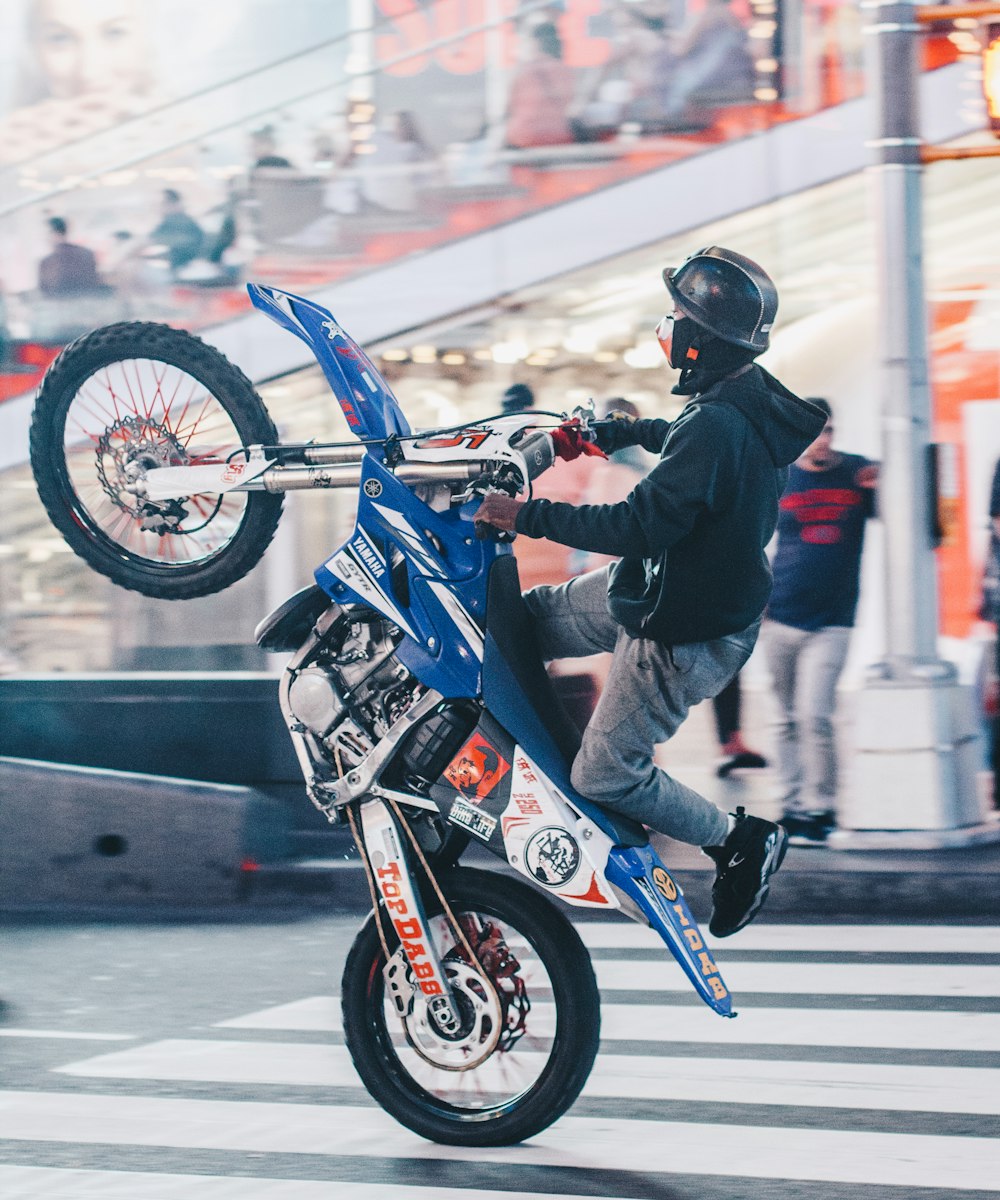 selective focus photography of man doing wheelie on motocross dirt bike