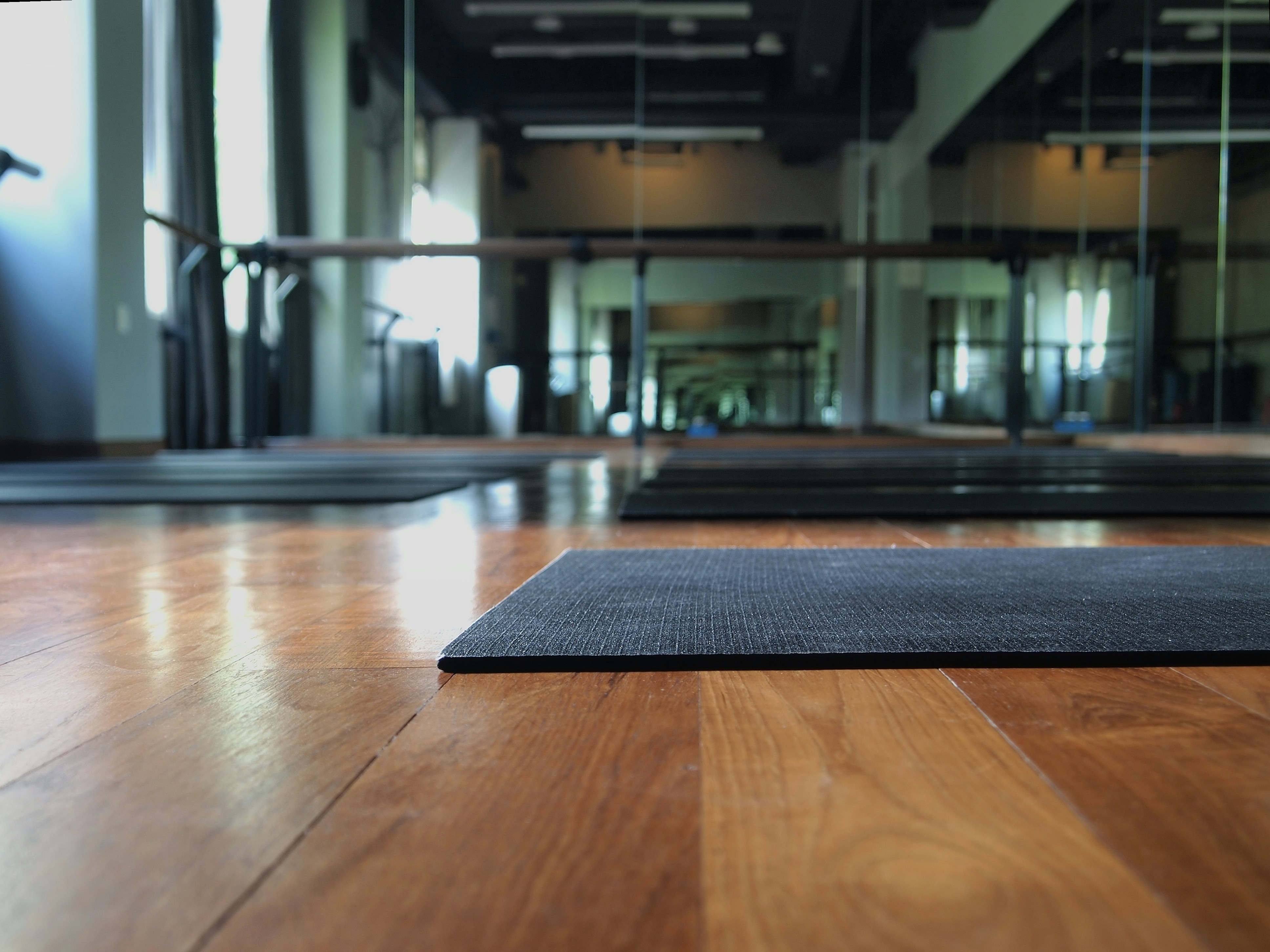 Purple yoga mat rolled out on wooden floor in bright airy studio