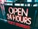A neon sign displays the words 'OPEN 24 HOURS' in bold, illuminated red and white letters. The sign is positioned outdoors, likely indicating the operating hours of a business. Reflections and shadows can be seen on the surrounding surfaces, and there's a faint glimpse of people and environment in the background.