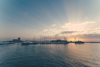 Sunset view over the historic Cádiz harbor with boats gently rocking on the water.