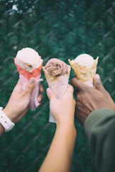 three people holding ice cream cones in their hands