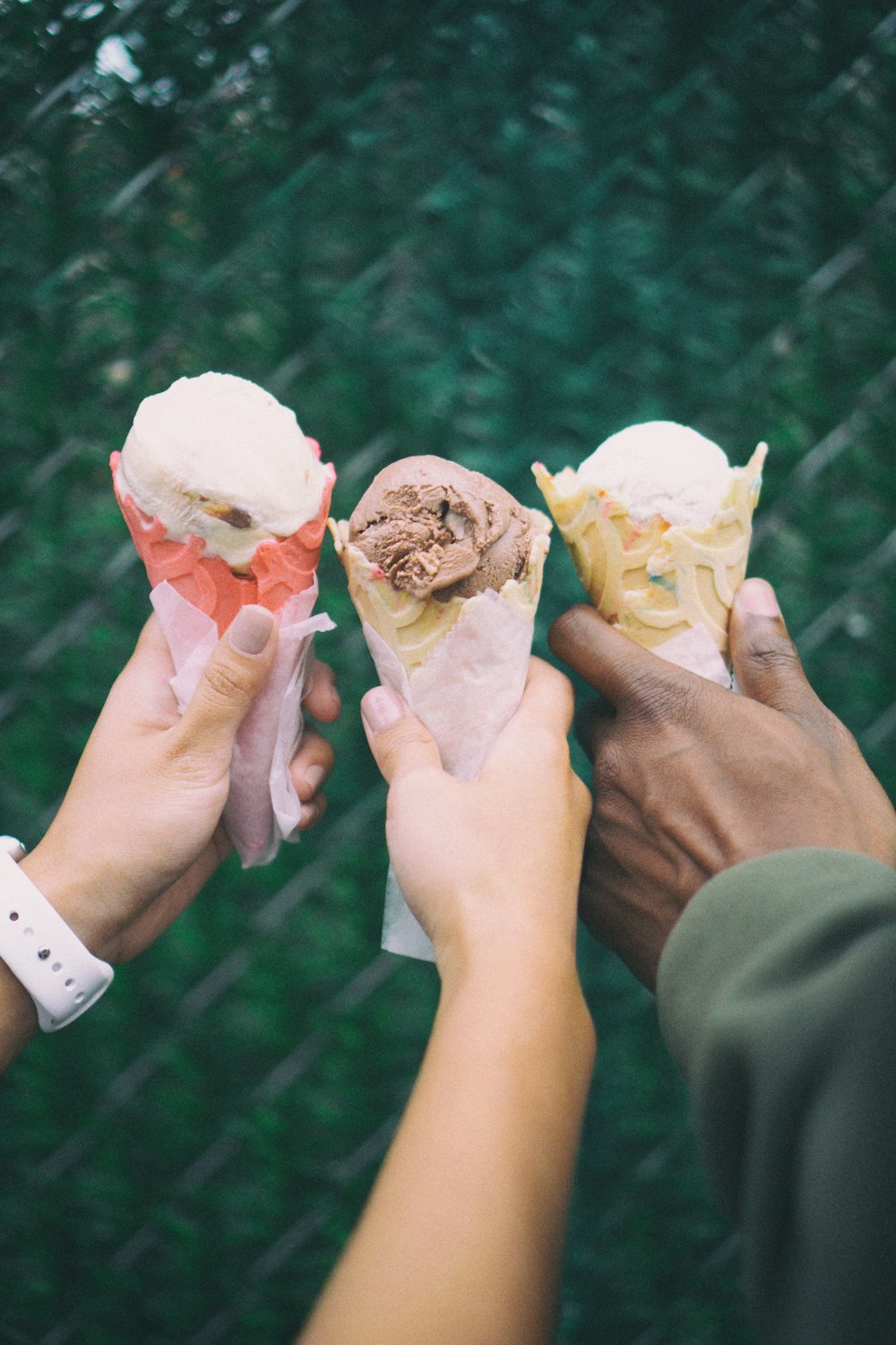 three people holding ice cream cones in their hands