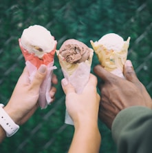 three people holding ice cream cones in their hands