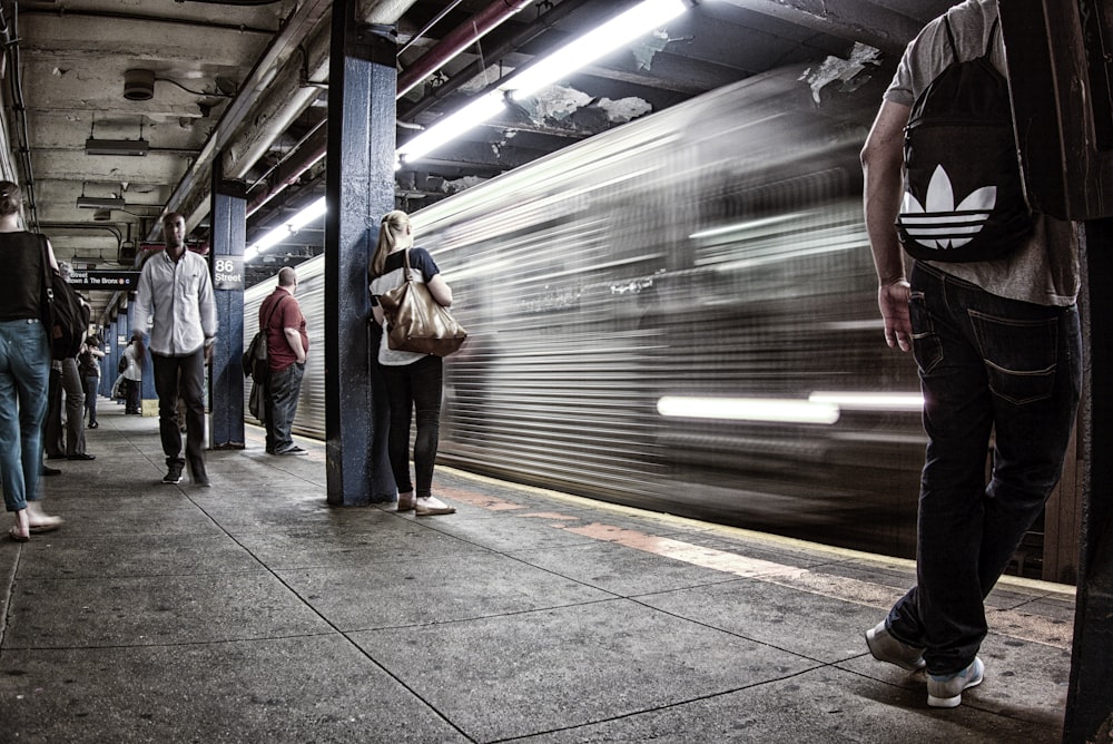 Fotografía de lapso de tiempo de tren al lado de personas en la estación