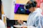 A visitor wearing headphones, immersed in a virtual art gallery experience on a laptop.
