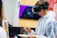 A visitor wearing headphones, immersed in a virtual art gallery experience on a laptop.