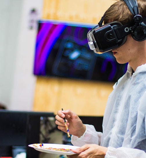 man wearing black virtual reality headset while painting near brown wall