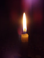A single candle flickering softly in a darkened room, evoking hope.
