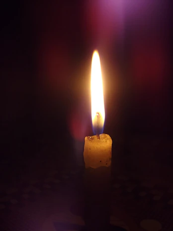 A quiet moment of reflection with a single candle glowing against a dark background.