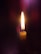 A close-up of a neshama candle flickering gently against a dark background.