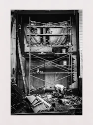 Black and white photo of construction site with workers and scaffolding.