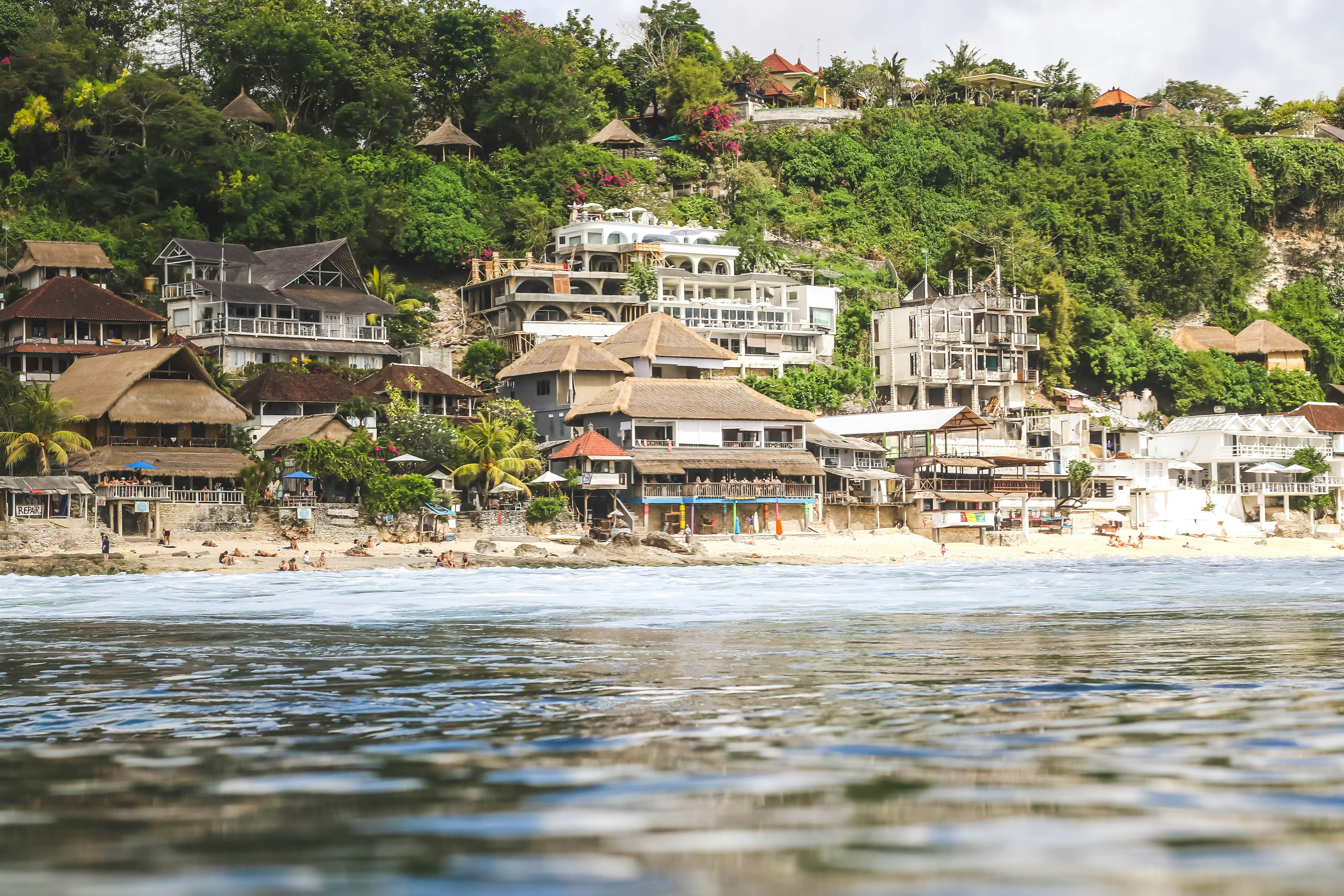 brown houses near sea, I shot this in the water of Binging Beach off the coast of Bali. The whole coast has been made into hotels and cafes to accompany all the surfers traveling in for vacation.
