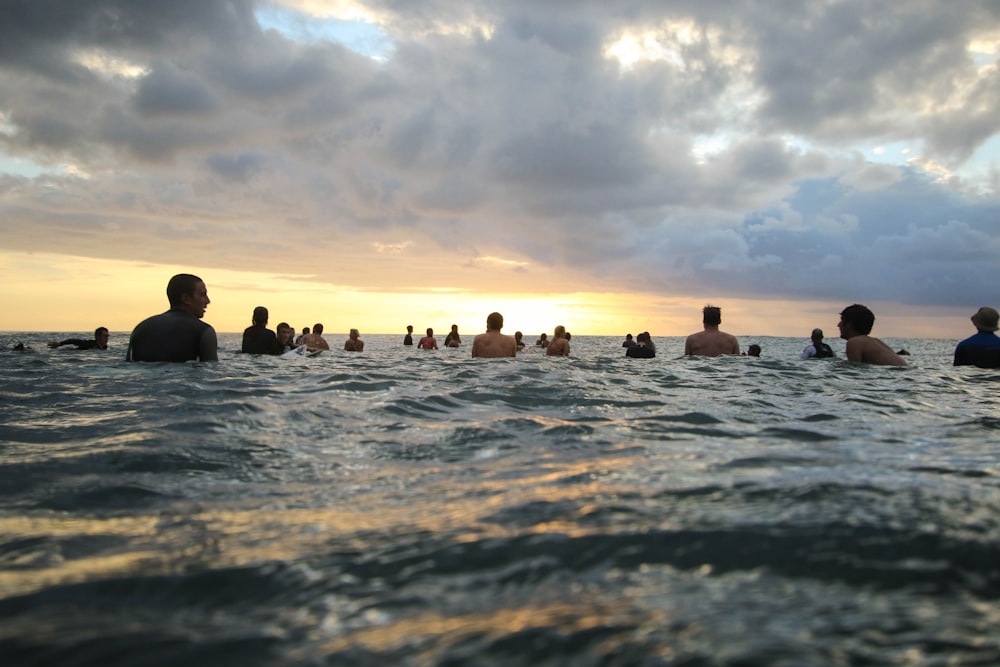 Gruppe von Menschen im Gewässer während des Sonnenuntergangs