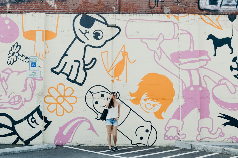 Photographie candide d’une femme debout contre un mur de graffitis avec un large sourire