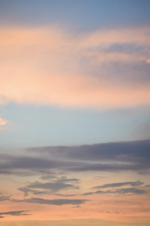 A panoramic view of a pastel dawn sky blending soft pinks and blues over a quiet airfield.