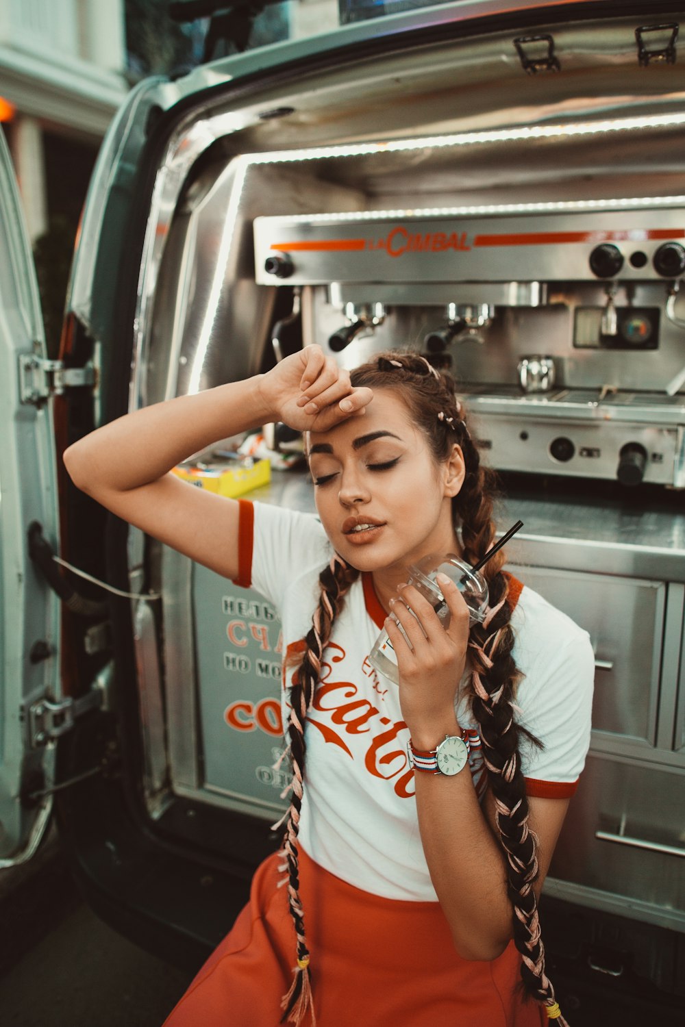 Woman in retro Coca Cola shirt wipes brow during a shift break