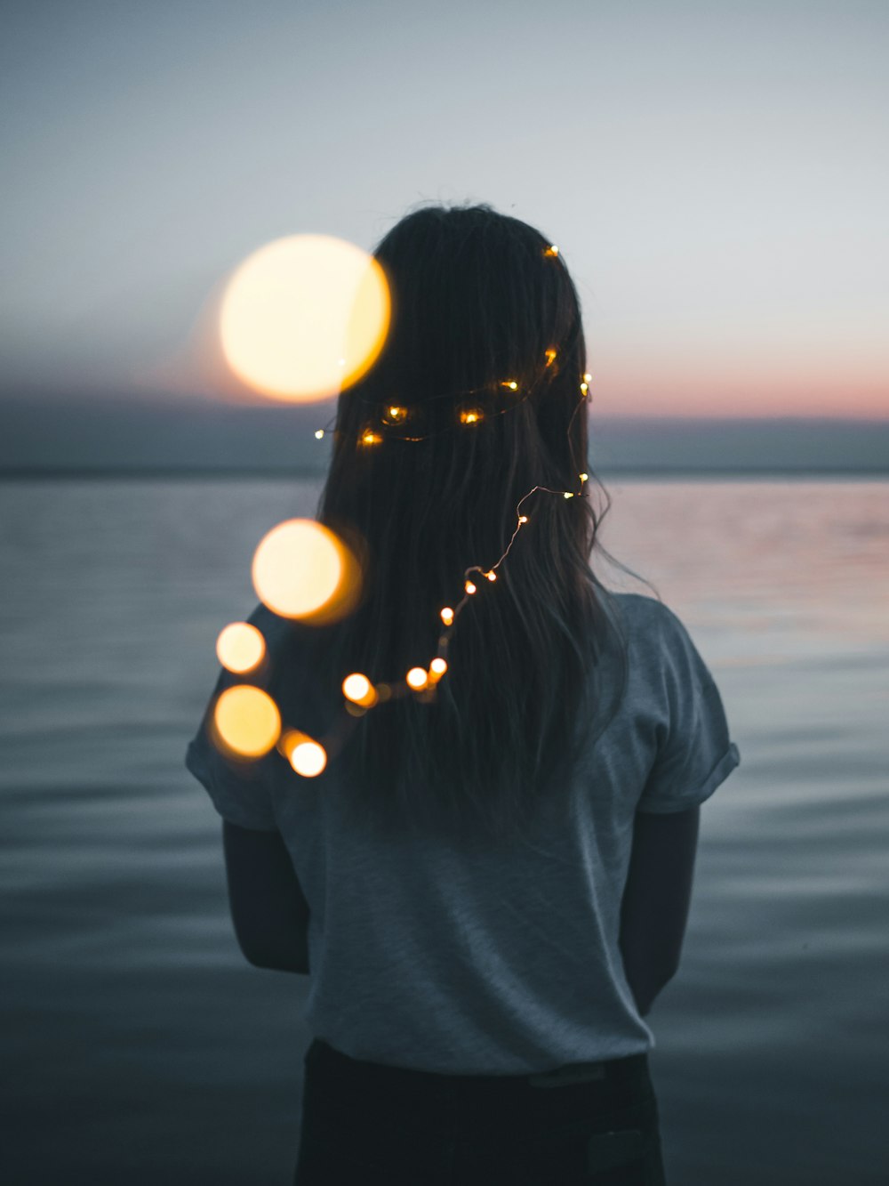 woman wearing white shirt facing the ocean photo during golden hour