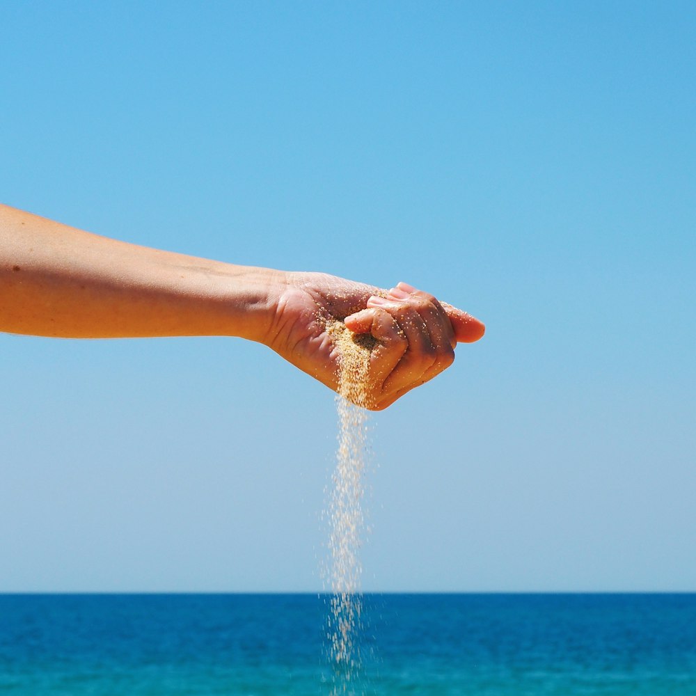 person holding brown sand during daytime