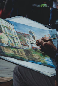 Close-up of an artist painting a vibrant cityscape on canvas.