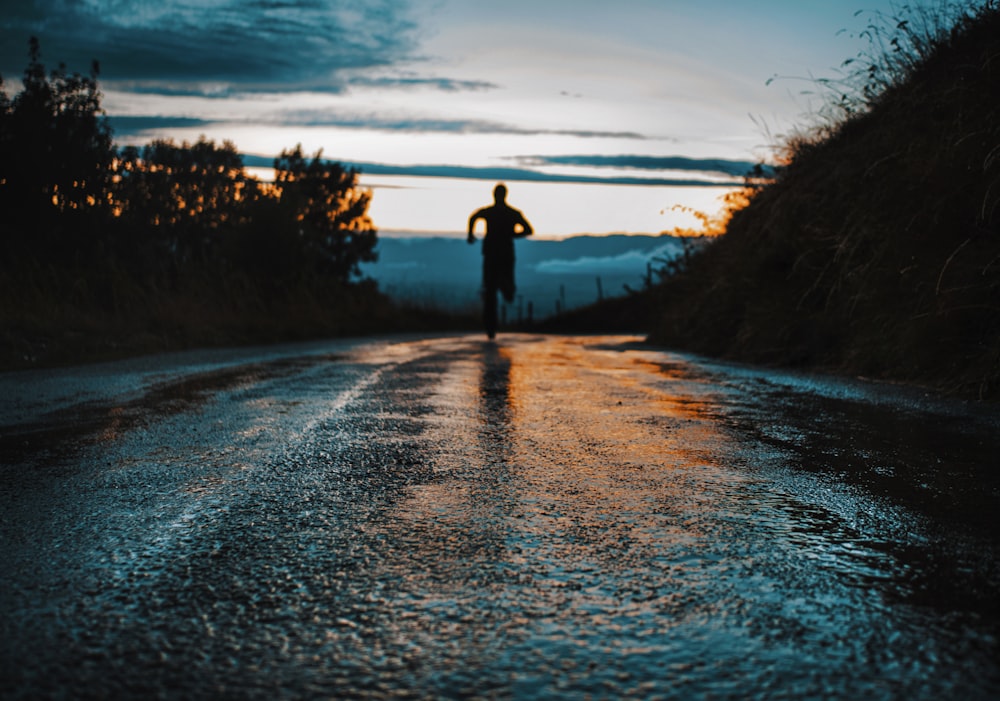 silhouette photo of a person running on road