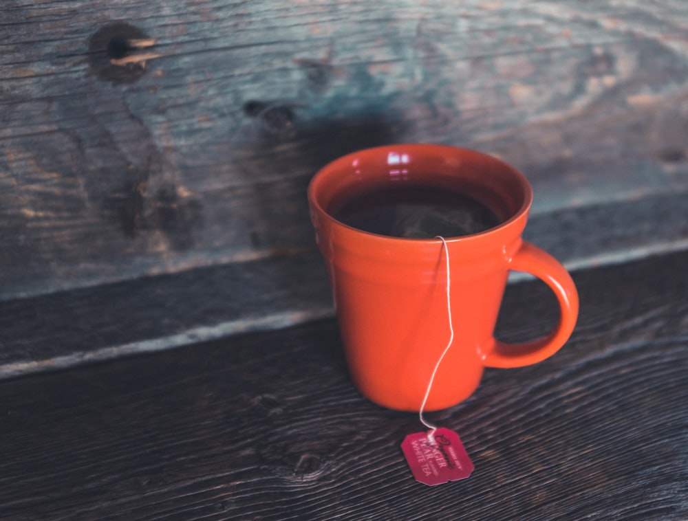 xícara de chá de cerâmica laranja no bord cinza