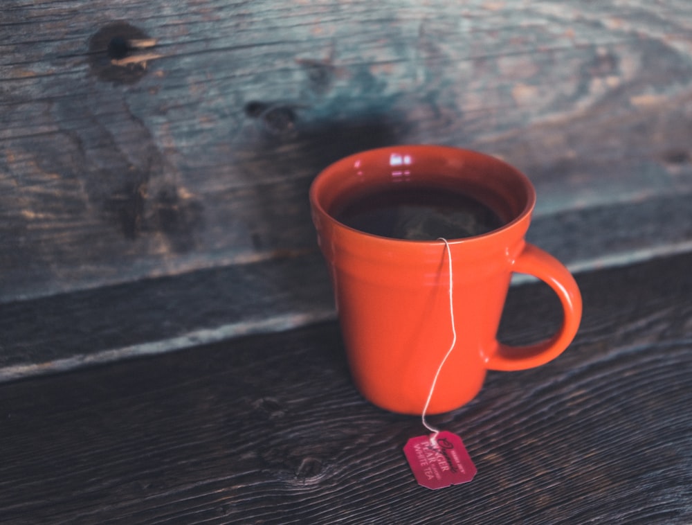 orange ceramic teacup on gray bord