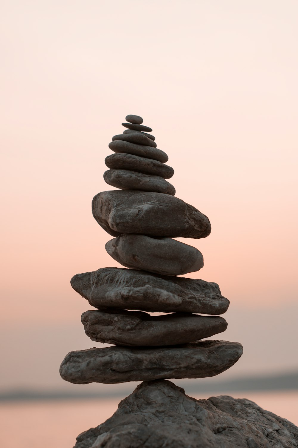 A stack of rocks against a pink sky