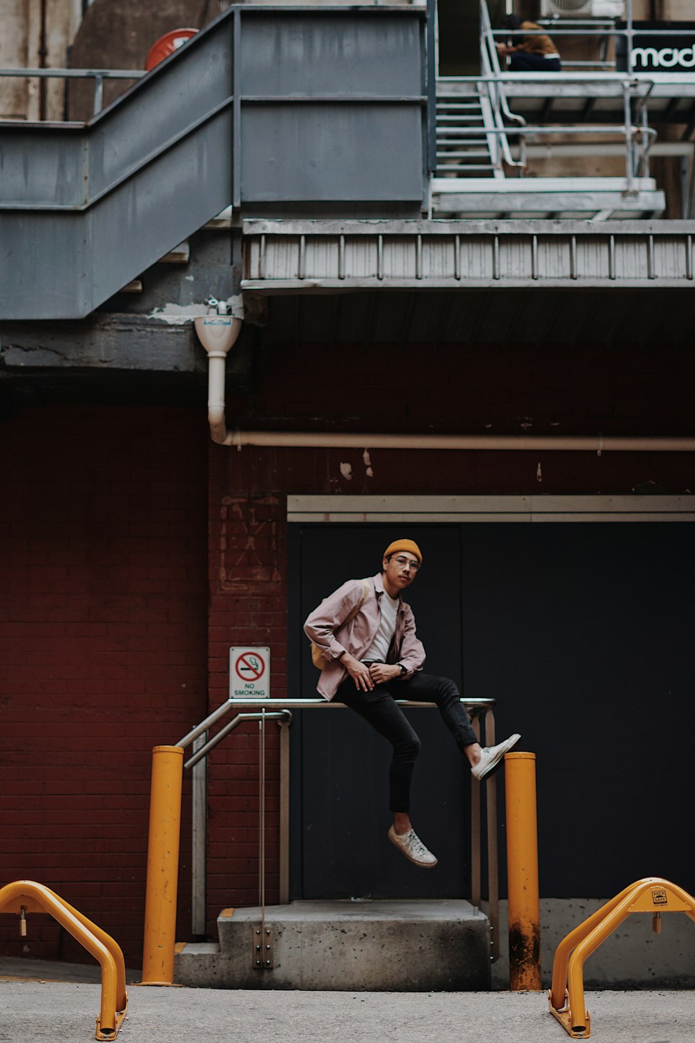 man sitting on railing in front of building