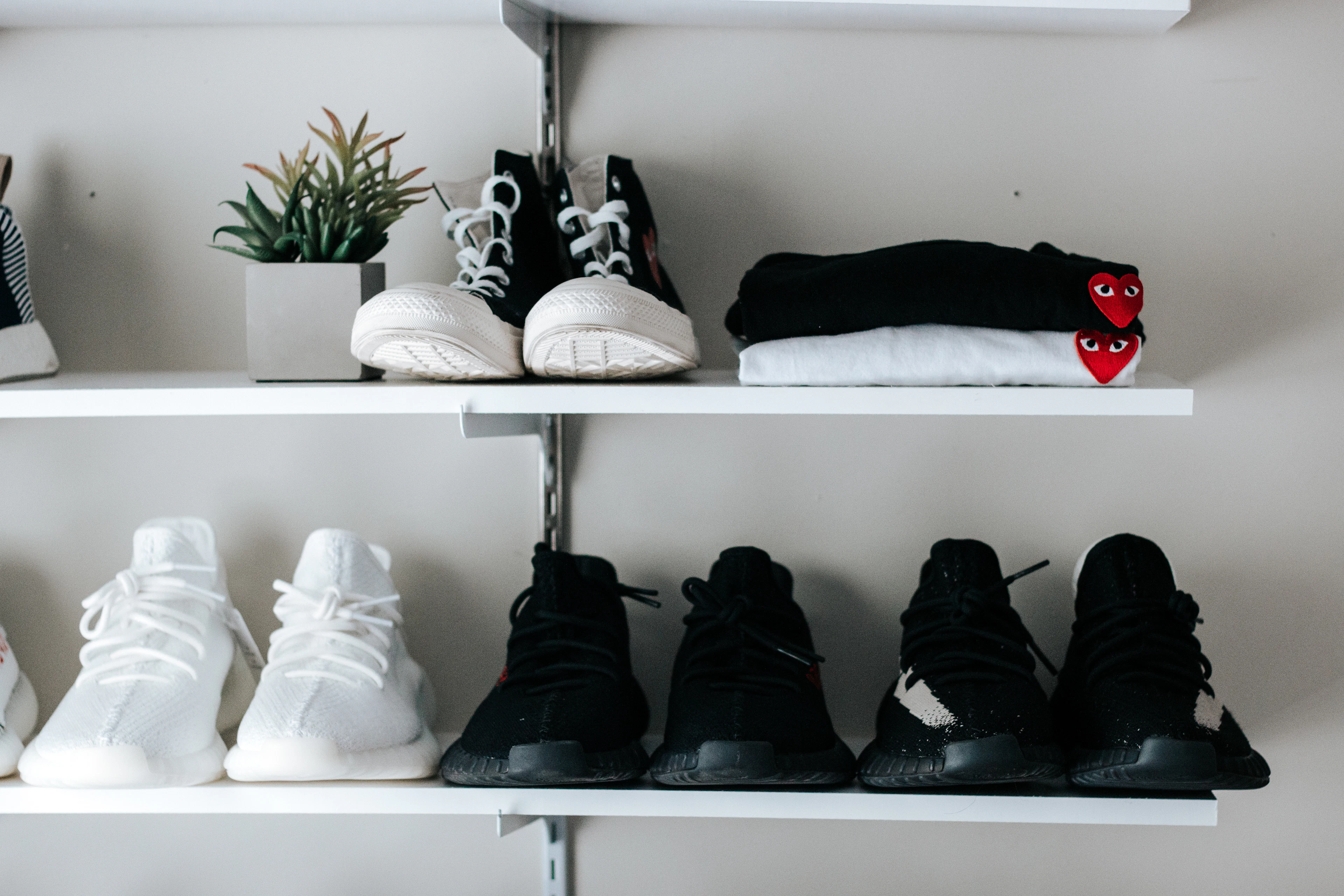 Pairs of black and white shoes arranged on white floating shelves