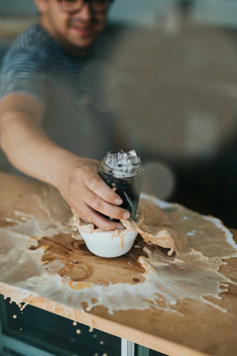 man holding clear glass jar putting on white ceramic bowl on brown wooden table