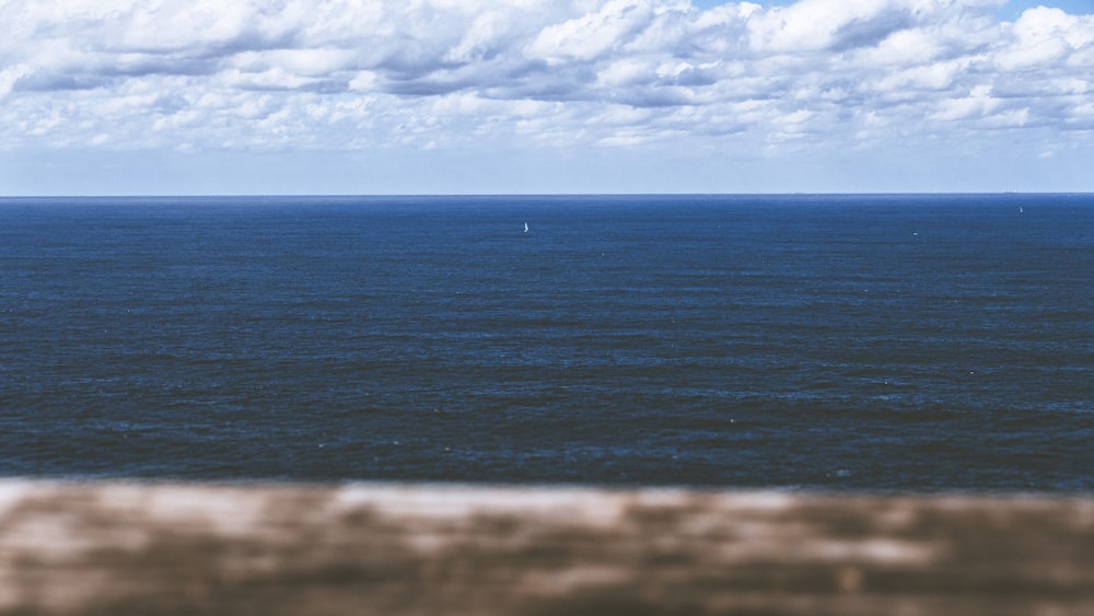 Cuerpo de agua azul tranquilo con vistas al horizonte bajo el cielo nublado durante el día