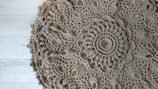 A finished lace doily laid out on a rustic fabric background.