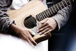 Close-up of hands playing a calming acoustic guitar.