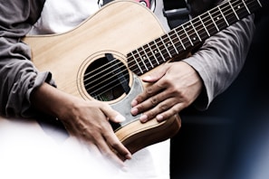 A close-up of a musician's hands playing an acoustic guitar.