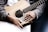 Close-up of hands playing an acoustic guitar with sheet music nearby.