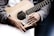 Close-up of hands playing an acoustic guitar with sheet music nearby.