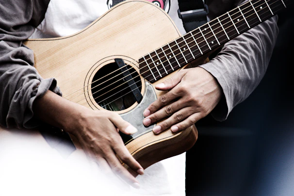 A close-up of hands playing an acoustic guitar in a cozy studio setting.