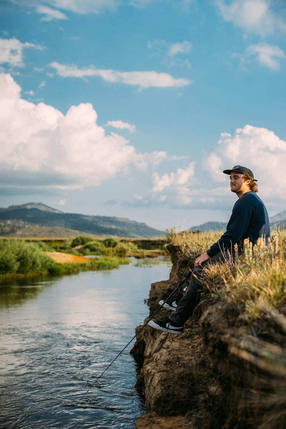 man in blue sweater sitting on rock during daytime