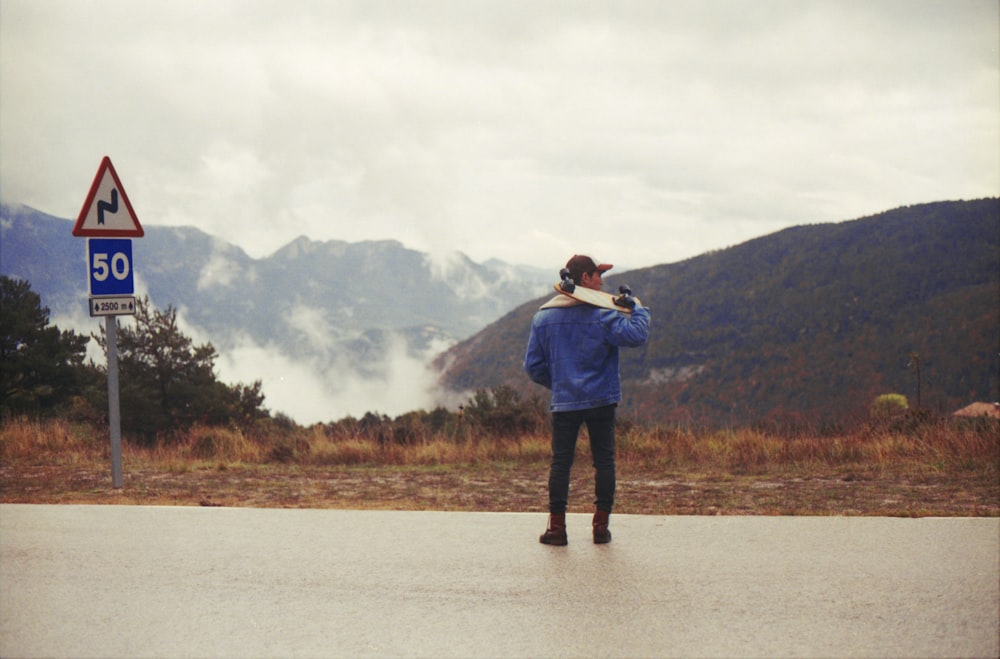 man in blue jacket carrying skateboard