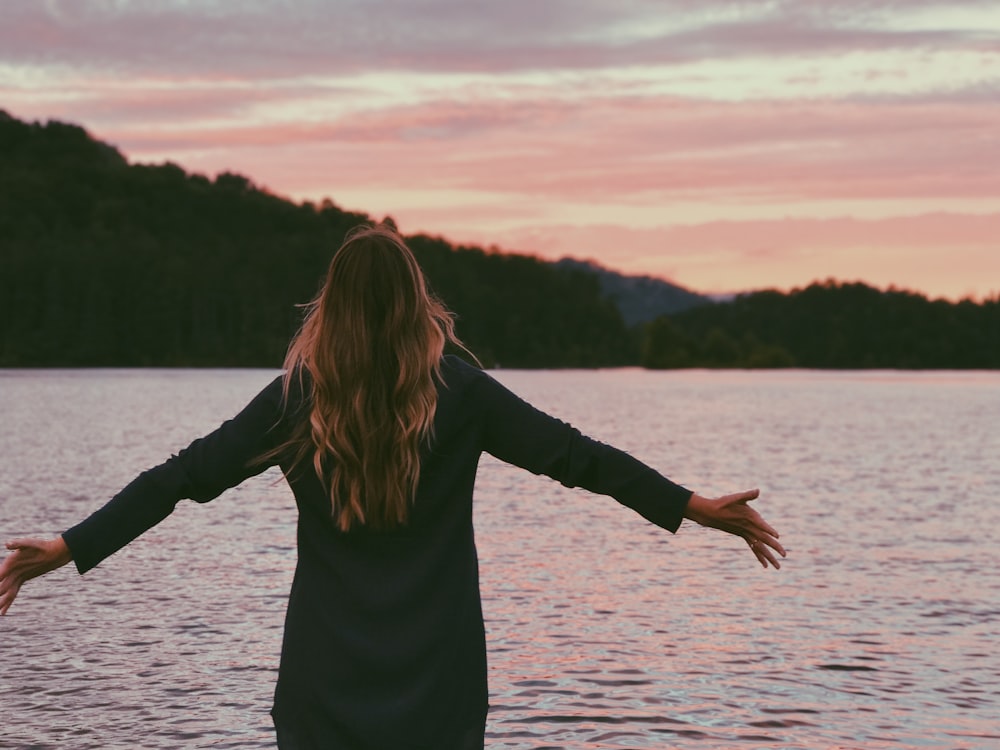 femme portant un manteau noir debout devant l’océan