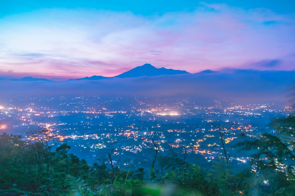 Foto de la montaña cerca de un árbol bajo el cielo azul