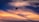 A person is parasailing against a dramatic sunset sky. The background features a mix of deep blues and vibrant oranges, creating a stunning contrast. The silhouette of the parasail and the rider is clearly visible, adding a sense of adventure and motion.