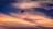 A person is parasailing against a dramatic sunset sky. The background features a mix of deep blues and vibrant oranges, creating a stunning contrast. The silhouette of the parasail and the rider is clearly visible, adding a sense of adventure and motion.