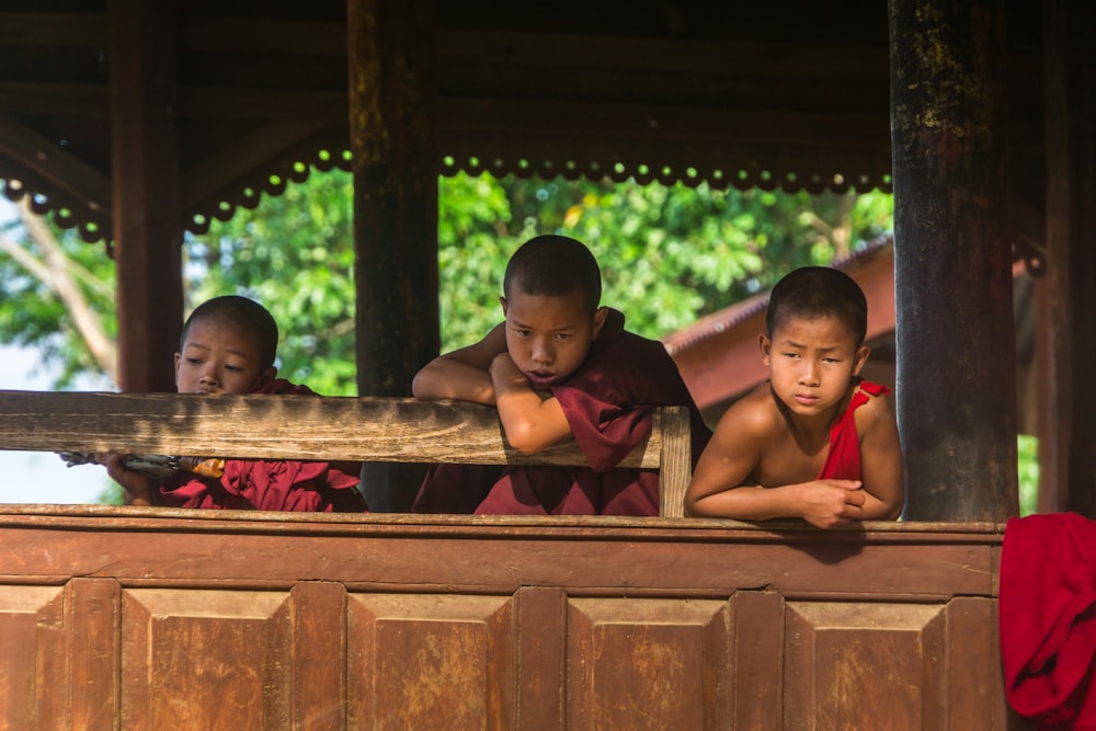 boys leaning on brown wooden board