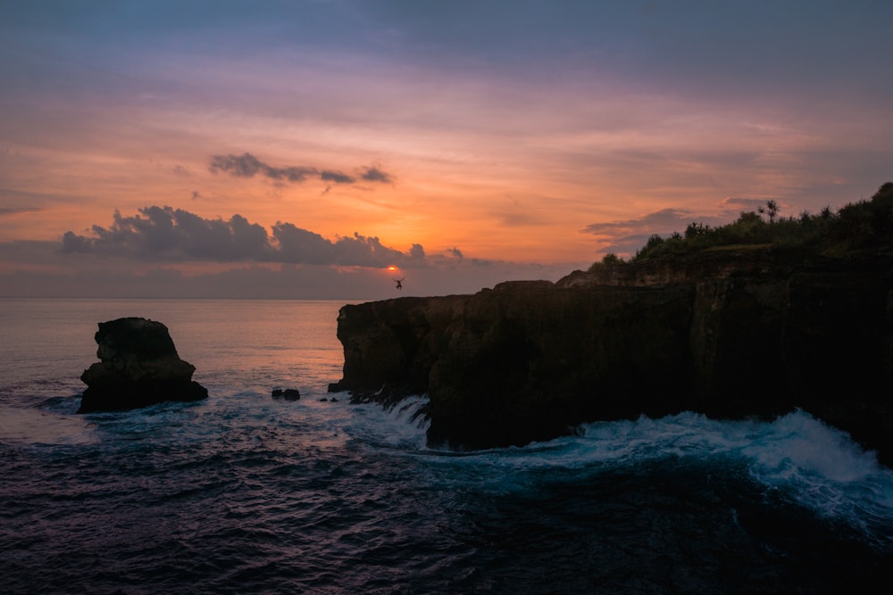 body of water splashing on rocks during golden hour