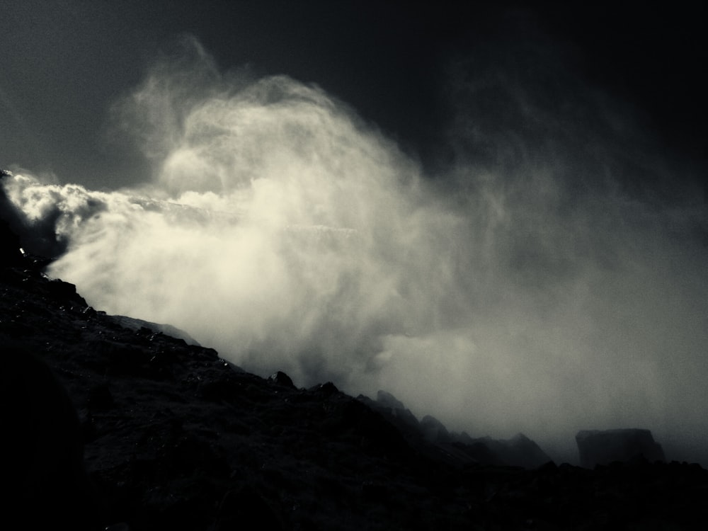 Foto en escala de grises de una colina bajo cielos nublados
