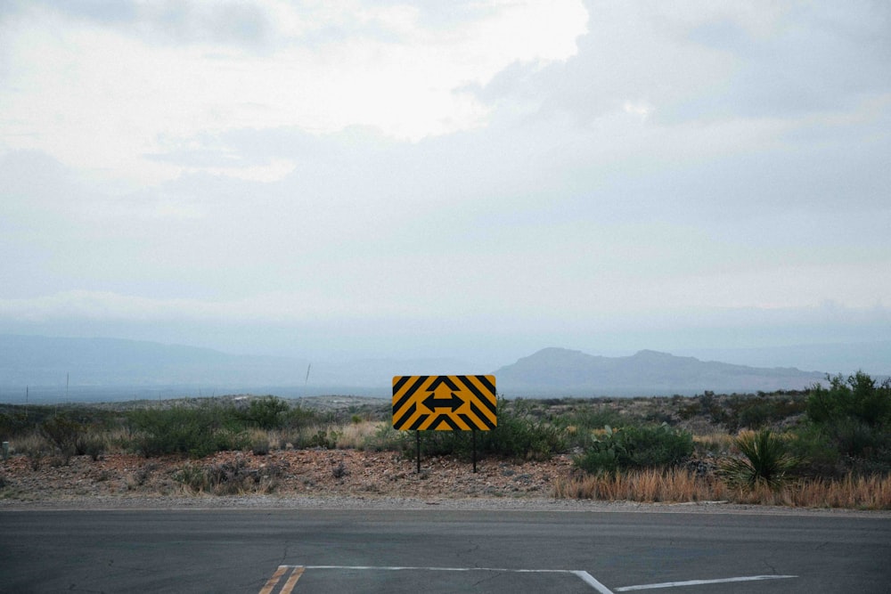 a yellow and black sign sitting on the side of a road