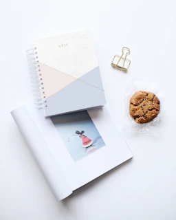 cookie beside two notebooks on white surface