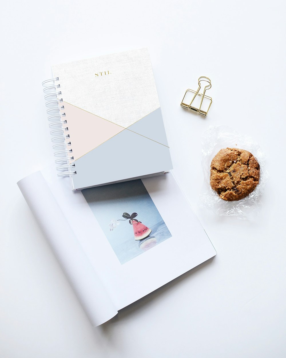 galleta junto a dos cuadernos sobre superficie blanca