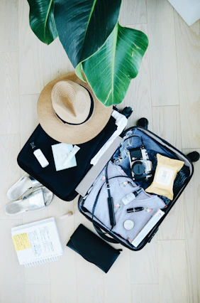 open suitcase with travel essentials and hat